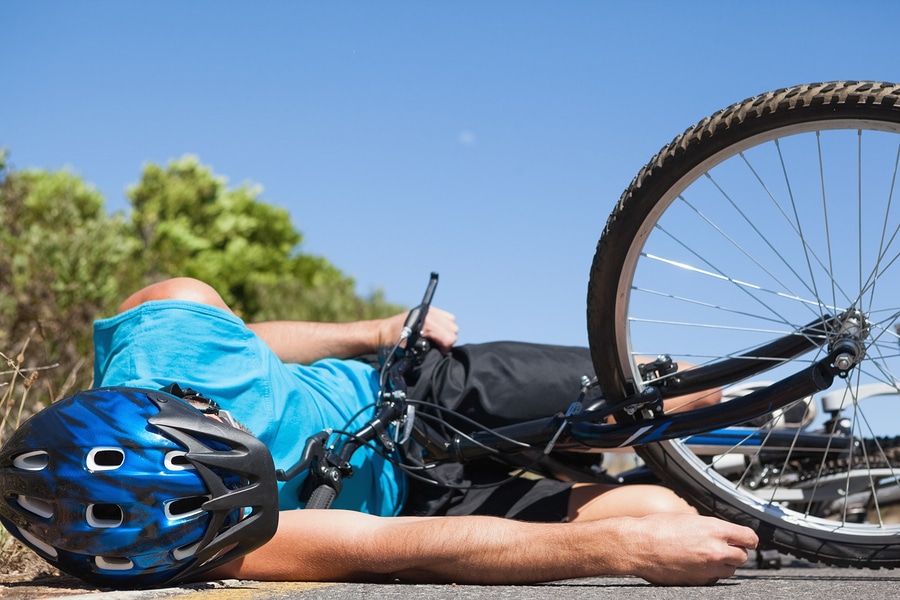 Cyclist lying on the road after an accident on a sunny day